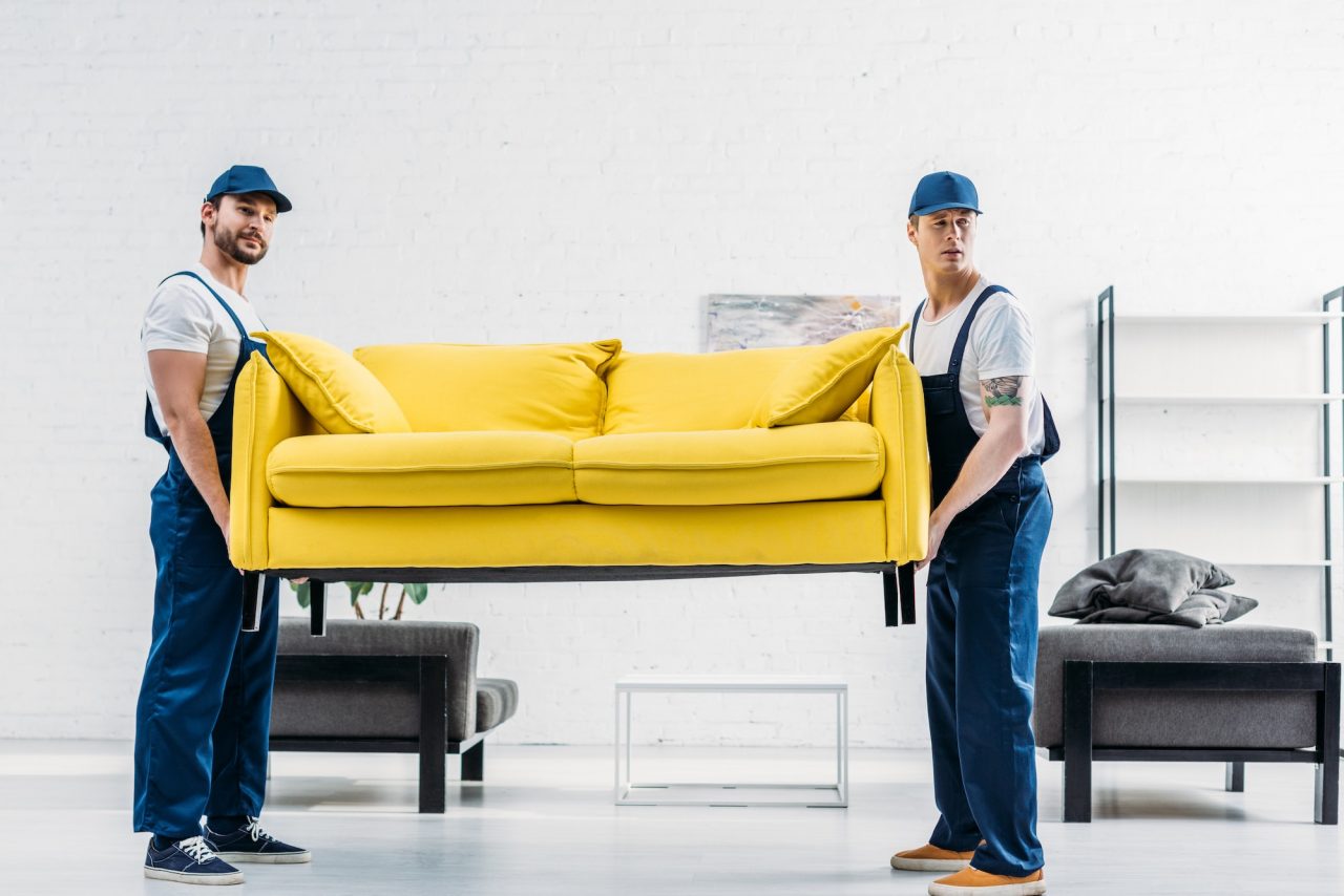 two-movers-in-uniform-transporting-couch-i
